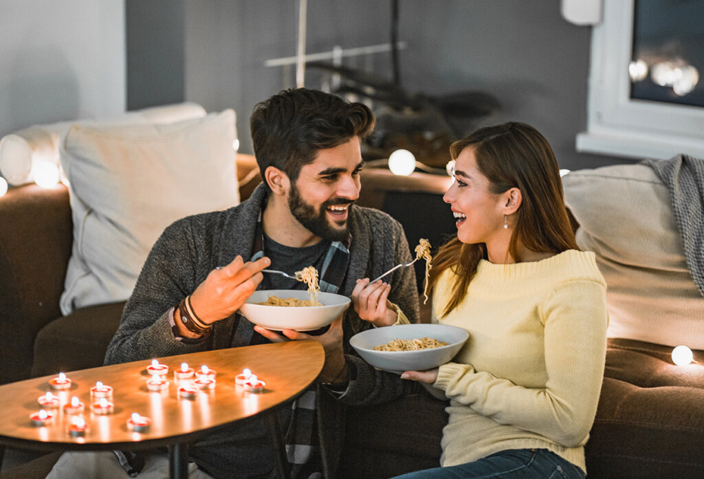 A young couple is at home, they are enjoying their free time and eating dinner.